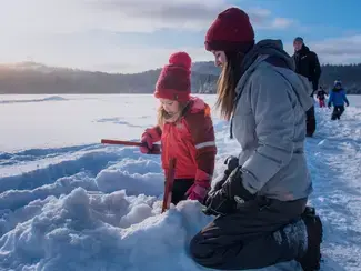 Deux petites filles pêchent sur la glace.