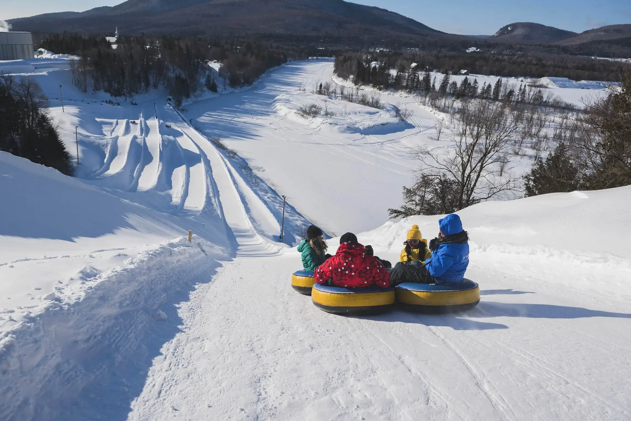 Quatre personnes dévalant des glissades sur neige.